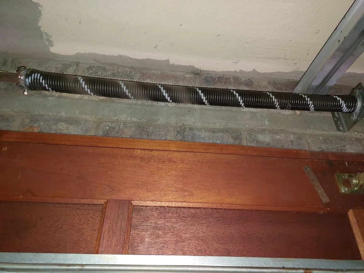 Torsion spring mounted around a garage door shaft