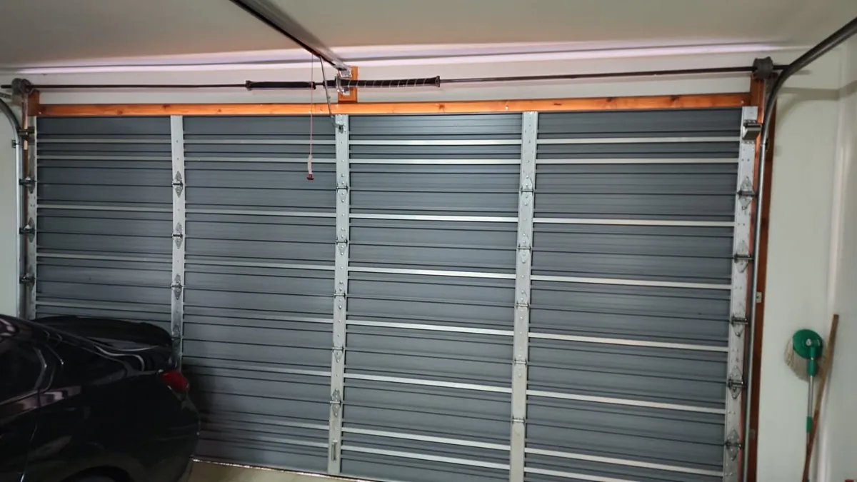 Interior of a steel sectional garage door showing panels, hinges and tracks