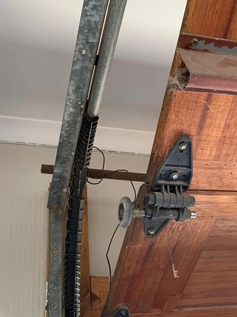 Roller bracket and track on a wooden sectional garage door