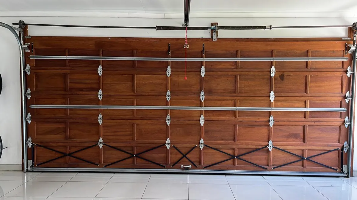 Interior of a wooden sectional garage door showing hinges and reinforcement bars